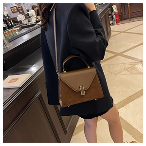 Detail view of vintage dark brown Kelly bag with mixed leather texture on a woman's shoulder