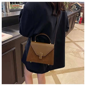 Detailed side view of a brown contrast leather handbag with golden lock and shoulder strap