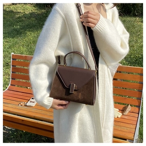 Detail of dark brown patchwork crossbody bag styled with a creamy fleece cardigan