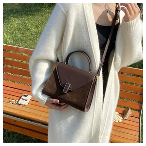 Detail of dark brown leather crossbody bag with suede stitching and metallic buckle