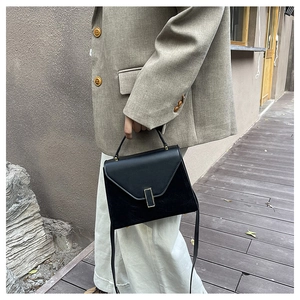 Detailed close-up of a matte black Kelly bag with gold buckle and leather texture