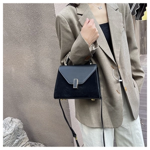 Detail of black trapezoid Kelly bag with leather contrast and gold hardware on model