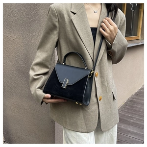 Detail of black contrast texture handbag with gold buckle and adjustable strap