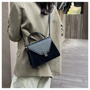 Minimalist black trapezoid bag in matte and smooth leather on a khaki blazer model