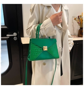 Detail of emerald green crocodile embossed V-shape patchwork handbag with gold clasp