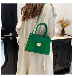 Detailed view of green crocodile texture handbag with gold buckle in lifestyle setting