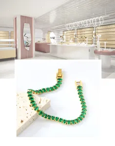 Détail d'un bracelet vintage en or avec pierres ovales vert émeraude sur pierre travertin