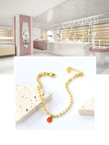 Bracelet à billes en acier doré avec pendentif coccinelle rouge en émail