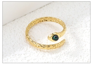 Macro shot of gold snake ring with green stone inlay and textured scale detailing