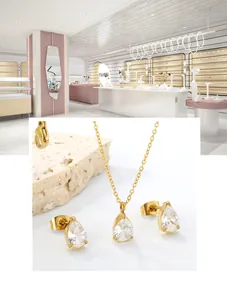 Close-up of gold drop-shaped necklace and stud earrings set with white zirconia