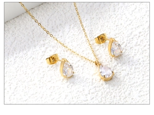 Macro detail of teardrop clear zircon necklace and stud earrings set in gold finish