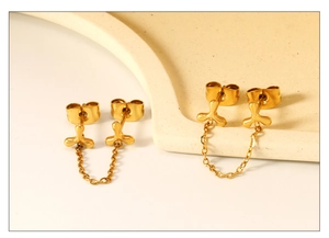 Detailed macro view of gold-plated boomerang stud earrings with tassel chains for double piercings