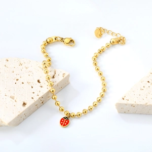 Bracelet à billes en acier doré avec pendentif coccinelle rouge et fermoir mousqueton