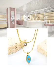 Dettaglio di una collana a doppio strato dorata con ciondoli occhio blu e zircone