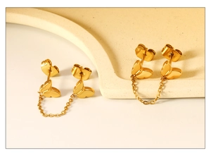 Close-up of golden butterfly double stud earrings with a delicate connecting link chain