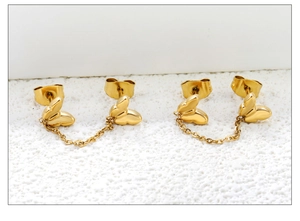 Detailed macro shot of gold butterfly double piercing earrings with delicate link chain