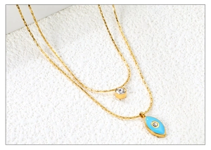 Dettaglio della collana a doppio strato in oro con ciondoli occhio blu e zircone