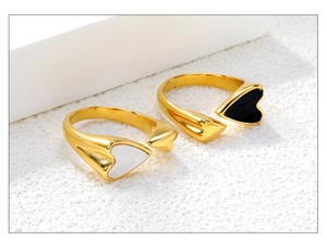 Detail van verstelbare gouden open ringen met hartvormige inlays van zwart en wit schelp
