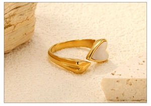 Macro-opname van een goudkleurige ring met hartvormige parelmoeren inleg op een stenen basis