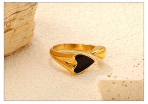 Macro-opname van gouden roestvrijstalen open ring met zwart emaille hartdetail