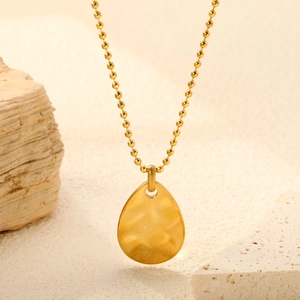Golden teardrop pendant necklace with hammered texture on beaded ball chain