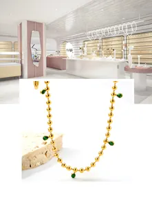 Macro detail of 18K gold beaded necklace with five emerald green teardrop pendants
