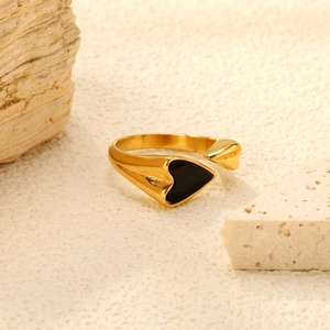Anello aperto dorato minimalista con cuore in smalto nero su sfondo di pietra testurizzata