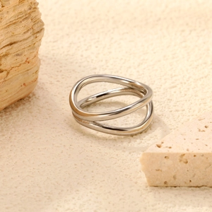 Minimalist double layer silver wave open ring on a textured sandstone background