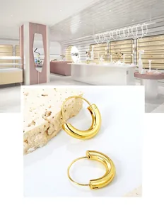 Macro detail of chunky gold hoop earrings with mirror polish finish on stone background
