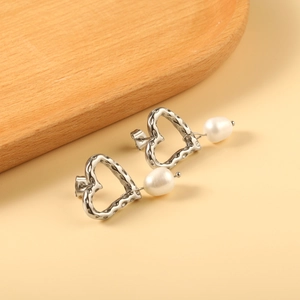 Dettagli di orecchini a cuore in argento martellato con perle bianche barocche