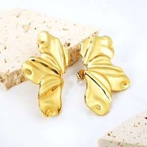 Golden irregular leaf earrings with liquid metal texture on white travertine stone