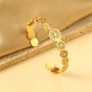 Vue détaillée d'un bracelet jonc doré avec motifs soleil gravés sur fond de soie douce