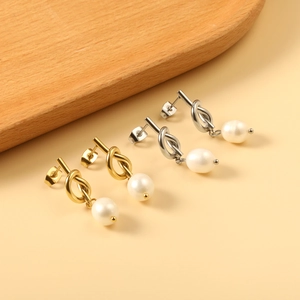 Boucles d'oreilles nœud élégantes en or et argent avec perles sur fond beige épuré