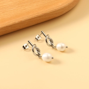 Détail de boucles d'oreilles nœuds argentés avec d'élégants pendentifs perles blanches
