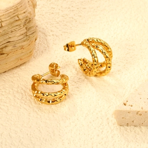 Irregular 18K gold-plated C-shaped earrings with layered textures on a stone surface