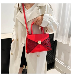 Detail of red crocodile texture crossbody bag with gold stud on white trench coat