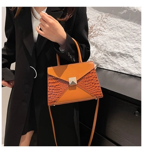 Detail of vibrant orange croc-embossed small square bag with silver metal buckle closure