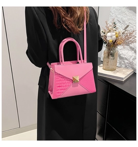 Pink crossbody bag with envelope flap and crocodile texture shown on a female model