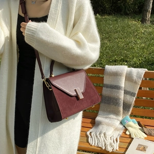 Elegant burgundy frosted leather Kelly bag with golden buckle on a wooden bench