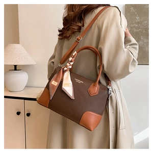 Dettaglio della borsa tote in pelle marrone con foulard in seta su modella in trench