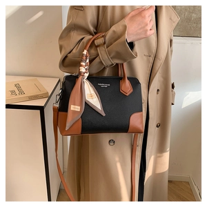 Dettaglio della borsa tote in pelle nera e marrone con foulard decorativo in seta sul manico