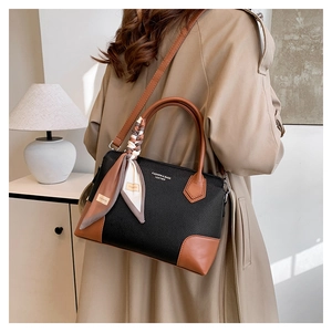 Dettaglio della borsa tote in pelle nera e marrone con manico in foulard di seta