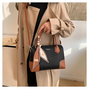 Dettaglio della borsa tote in pelle con manico in seta su modella con un trench