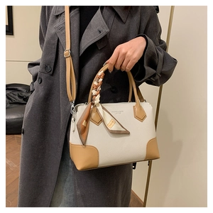 Dettaglio della borsa tote bianco sporco con cinturini in pelle cammello e sciarpa di seta