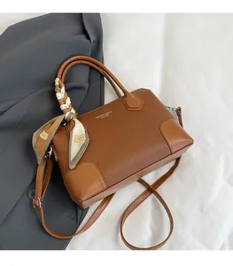 Dettaglio borsa tote in pelle marrone con foulard decorativo sul manico e logo