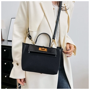 Detailed view of the vintage black trapezoid handbag showing gold metal twist lock buckle
