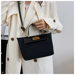 Close-up of the black handbag featuring a textured flap and polished gold twist-lock closure