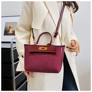 Detail view of burgundy matte suede and glossy leather textures with gold metal twist lock