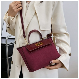Side view of model wearing a burgundy suede and leather crossbody bag with gold twist lock