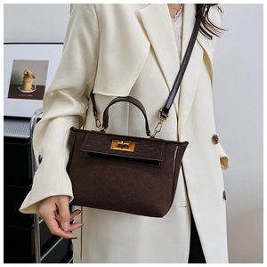 Detail of dark brown suede handbag with crocodile pattern flap and golden turn-lock